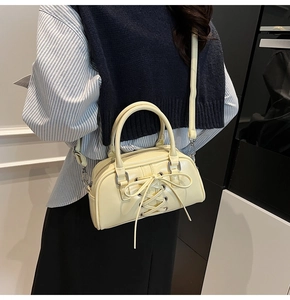 Dettaglio borsa a tracolla giallo pallido con fiocchi decorativi su ecopelle liscia
