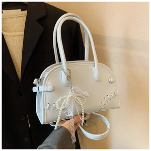 Détail du sac à main bleu clair avec pendentif perle et nœud en dentelle et coutures décoratives