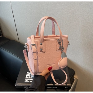 Detail of pink pebbled leather bucket bag with silver heart charm and adjustable strap