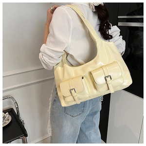 Detail of cream yellow glossy tote bag featuring functional front pockets and metal buckles