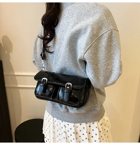 Back view of a glossy black patent leather crossbody bag showing size and fit on model