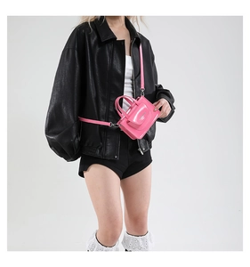 Detail einer Mini-Umhängetasche aus glänzendem rosa Lackleder mit verstellbarem Gurt