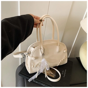 Détail du sac Boston blanc crème avec breloque en perles et dentelle et bandoulière amovible