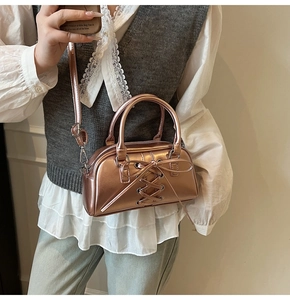 Modella con borsa Boston metallizzata oro rosa con fiocco e tracolla regolabile