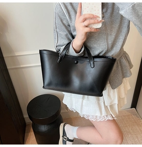Close-up of minimalist black matte leather tote bag being held for lifestyle demonstration