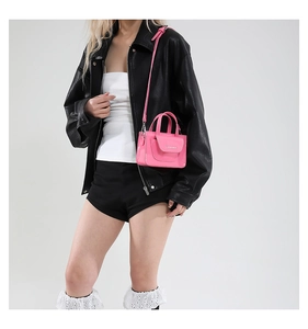 Detail der leuchtend rosa Mini-Umhängetasche aus Lackleder mit Metalllogo und Riemen