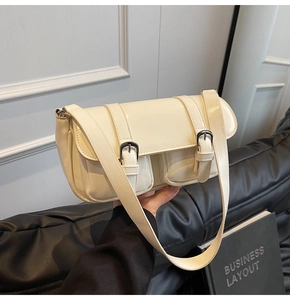 Detail of cream white patent leather shoulder bag with silver buckles and double pockets