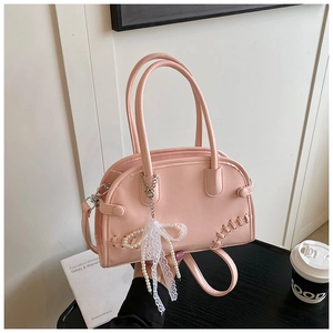 Détail du sac boston rose en cuir avec coutures croisées et breloque perle en dentelle
