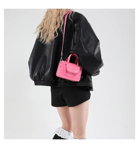 Bright pink mini crossbody bag with a glossy finish and adjustable strap shown on model