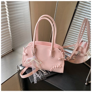 Détail du sac cabas rose clair avec coutures, breloque nœud perlé et pendentif dentelle