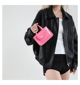 Bright pink patent leather mini crossbody bag styled with a modern black biker jacket