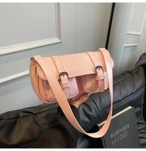 Close-up of bright pink messenger bag featuring decorative silver buckles and front pockets