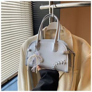 Détail du sac bandoulière gris-bleu avec coutures croisées et pendentif perle