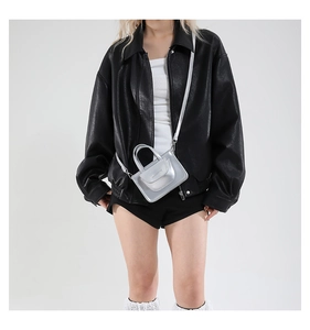 Detailaufnahme der metallisch silbernen Mini-Tasche im Kontrast zur Lederjacke