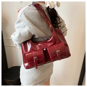 Detail view of burgundy leather shoulder bag with dual front pockets and silver buckles