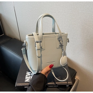 Detail of light green litchi texture handbag with silver chain and adjustable strap