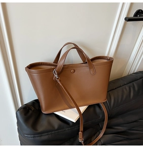 Detail of caramel brown leather tote bag with round handles on a textured stool