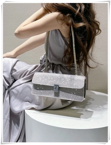 Detail of silver rhinestone evening bag with chain strap on a lavender dress model