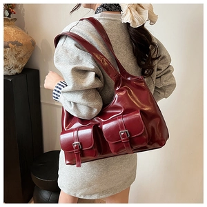 Detail of burgundy PU shoulder bag featuring decorative silver metal pin buckles