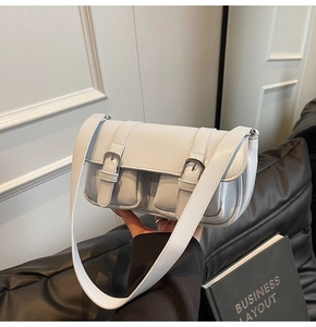 Detail of light blue crossbody bag with silver buckles and dual front pockets
