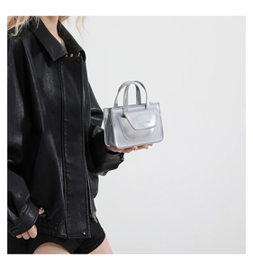 Detail of silver metallic mini bag with a front flap pocket and dual top handles