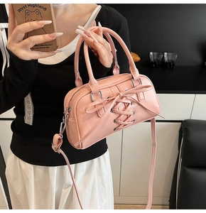 Dettaglio borsa a bauletto rosa con nastri intrecciati e fiocco decorativo