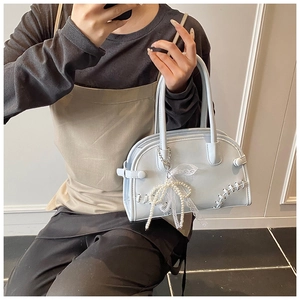 Détail du sac Boston bleu clair avec nœud en perles et accessoire de charme en dentelle