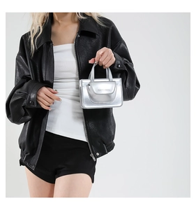 Detail of silver metallic mini handbag with top handle paired with a black leather jacket