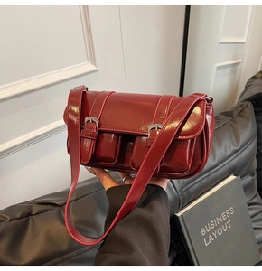 Close-up of shiny red patent leather shoulder bag with decorative front dual pockets