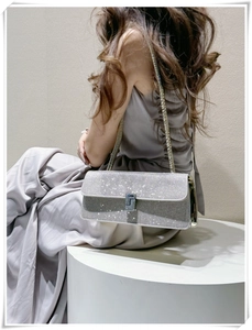 Detail of silver rhinestone evening bag with metal chain strap shown on model shoulder