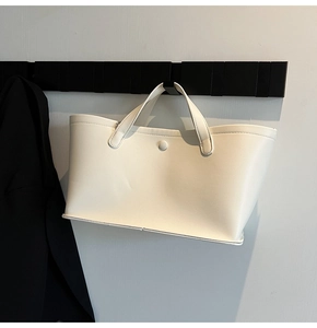 Close-up of minimalist white leather bucket bag with snap button and dual handles