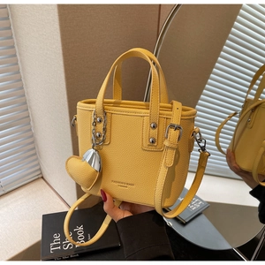 Detail of yellow lychee textured bucket bag with heart pendant and metal chain