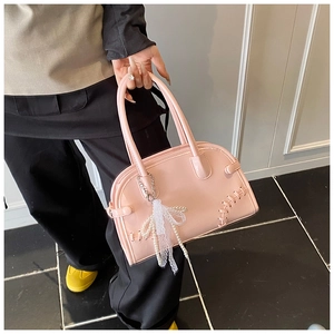 Détail du sac à main rose en cuir avec nœud en dentelle perlé et coutures tressées