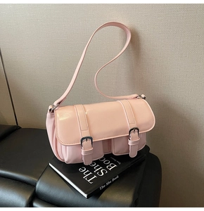 Close-up of pink leather shoulder bag with decorative straps on books in soft light