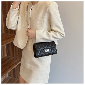 Détail d'un sac bandoulière noir matelassé avec chaîne en perles et fermoir en métal