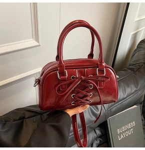 Dettaglio borsa Boston bordeaux con lacci incrociati e occhielli in argento