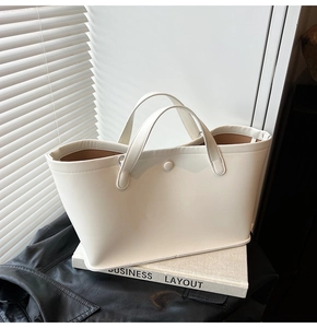 Close-up of white leather tote bag set on book with natural sunlight and shadow