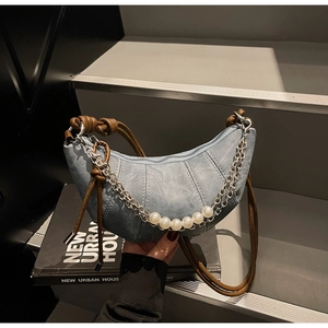 Détail du sac croissant en denim bleu clair avec chaînes argentées et perles