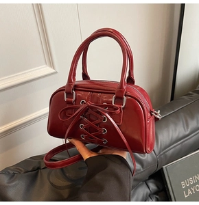 Dettaglio della borsa in pelle verniciata bordeaux con fiocco e fibbie in metallo argento