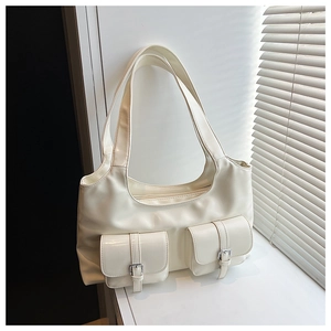 Detail of cream semi-moon underarm bag with metal buckle pockets in natural soft light