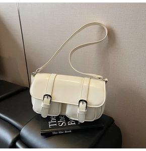 Detail of a creamy white retro underarm bag with decorative buckles and dual small pockets