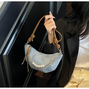 Détail du sac croissant en denim bleu clair avec chaînes argentées et perles blanches
