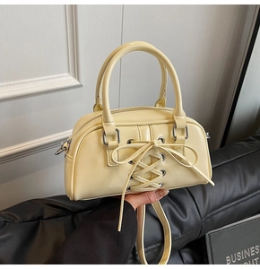 Dettaglio della borsa in pelle giallo crema con lacci a occhielli stile corsetto