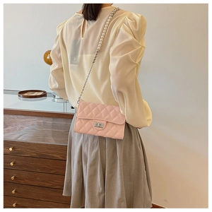 Détail du sac bandoulière rose matelassé avec chaîne de perles et de métal de luxe porté
