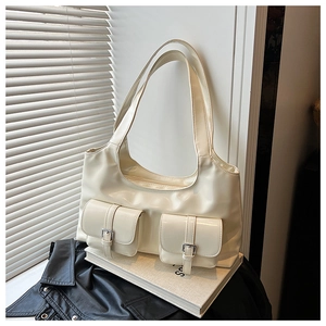 Detail shot of a cream white PU leather tote bag with silver buckles and elegant shadows
