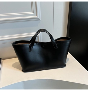 Detailed view of black minimalist PU leather tote bag with elegant handle and metal snap
