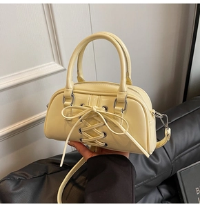Dettaglio borsa Boston in vernice giallo crema con lacci incrociati sul davanti