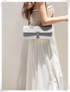 Silver sequined baguette bag with metal buckle shown on model wearing white dress