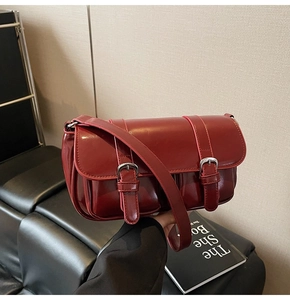 Detail of burgundy vintage messenger bag with silver buckles and smooth synthetic leather finish