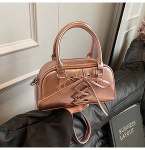 Dettaglio borsa metallizzata oro rosa con fiocco a nastro e occhielli in argento